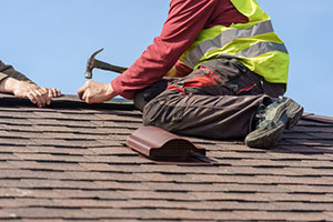 Man hammering nail on roof of home.