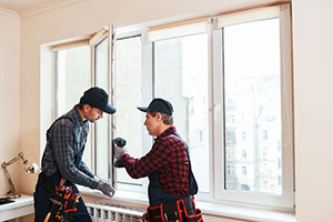Repair men fixing replacement window at home.